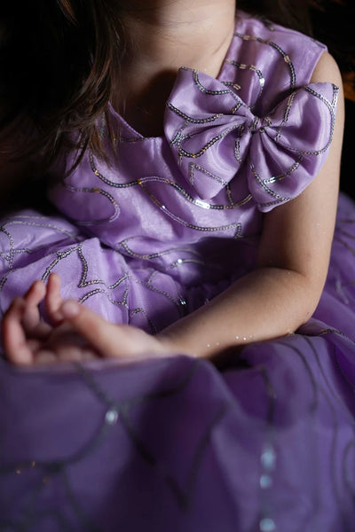 Close-up of a person wearing a purple dress with decorative elements.