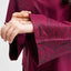 Close-up of a burgundy dress with intricate black patterns on a white background