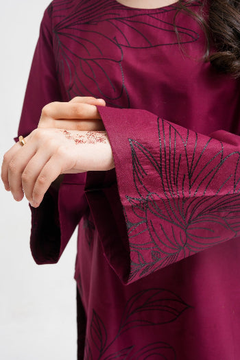 Close-up of a burgundy dress with intricate black patterns on a white background