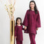 Woman and child in matching maroon outfits standing next to a gold vase with decorative branches on a white background
