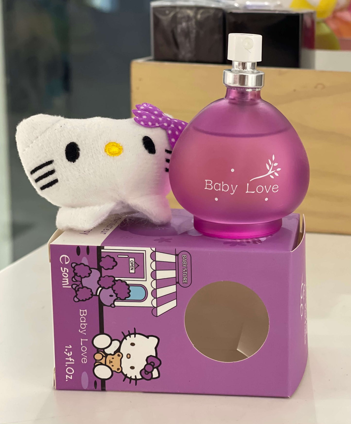 Purple 'Baby Love' perfume bottle with Hello Kitty plush toy on a matching box.
