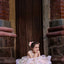 Young girl in a white dress sitting on stone steps with a brick wall background