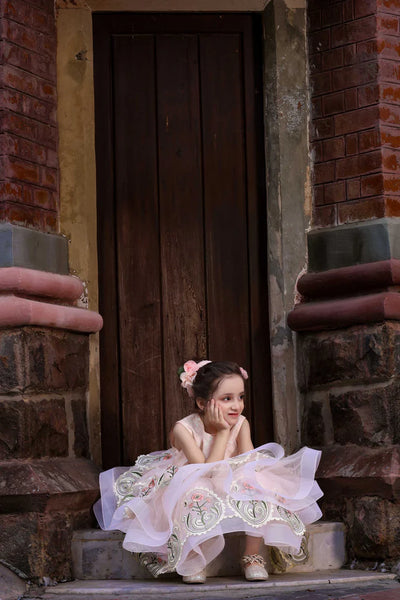 Young girl in a white dress sitting on stone steps with a brick wall background