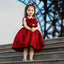 Young girl in a red dress standing on steps with a blurred background