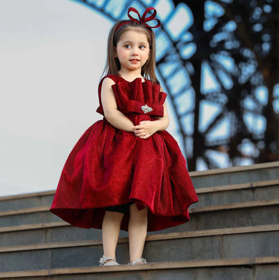 Young girl in a red dress standing on steps with a blurred background