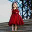 Young girl in a red dress standing on steps with a blurred background