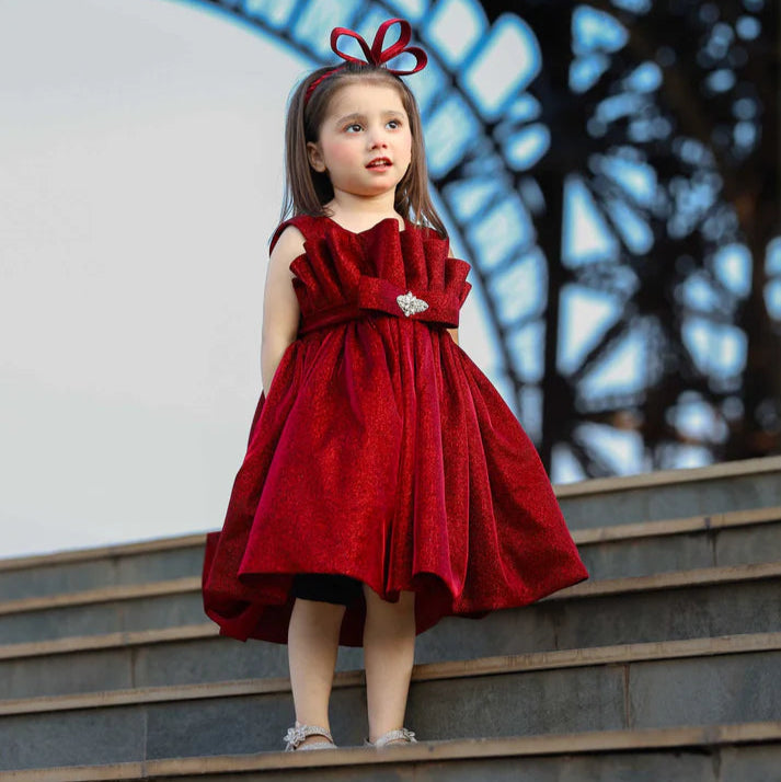 Young girl in a red dress standing on steps with a blurred background
