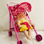 Toy doll in a pink stroller with a checkered canopy on a light background