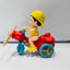 Toy figure of a child on a red motorcycle with blue wheels against a white background