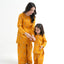 Woman and child in matching yellow outfits on a white background