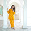 Woman in a yellow traditional outfit standing in front of an archway.
