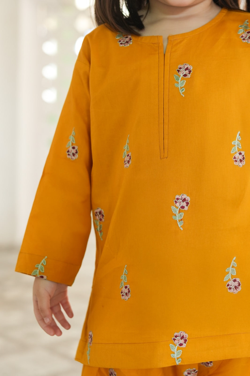 Yellow kurta with floral embroidery on a blurred background