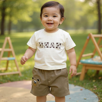 Child wearing a shirt with 'BEAR' printed on it in a park setting