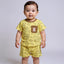 Baby wearing a yellow outfit with bear patterns on a plain background
