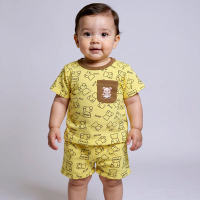 Baby wearing a yellow outfit with bear patterns on a plain background